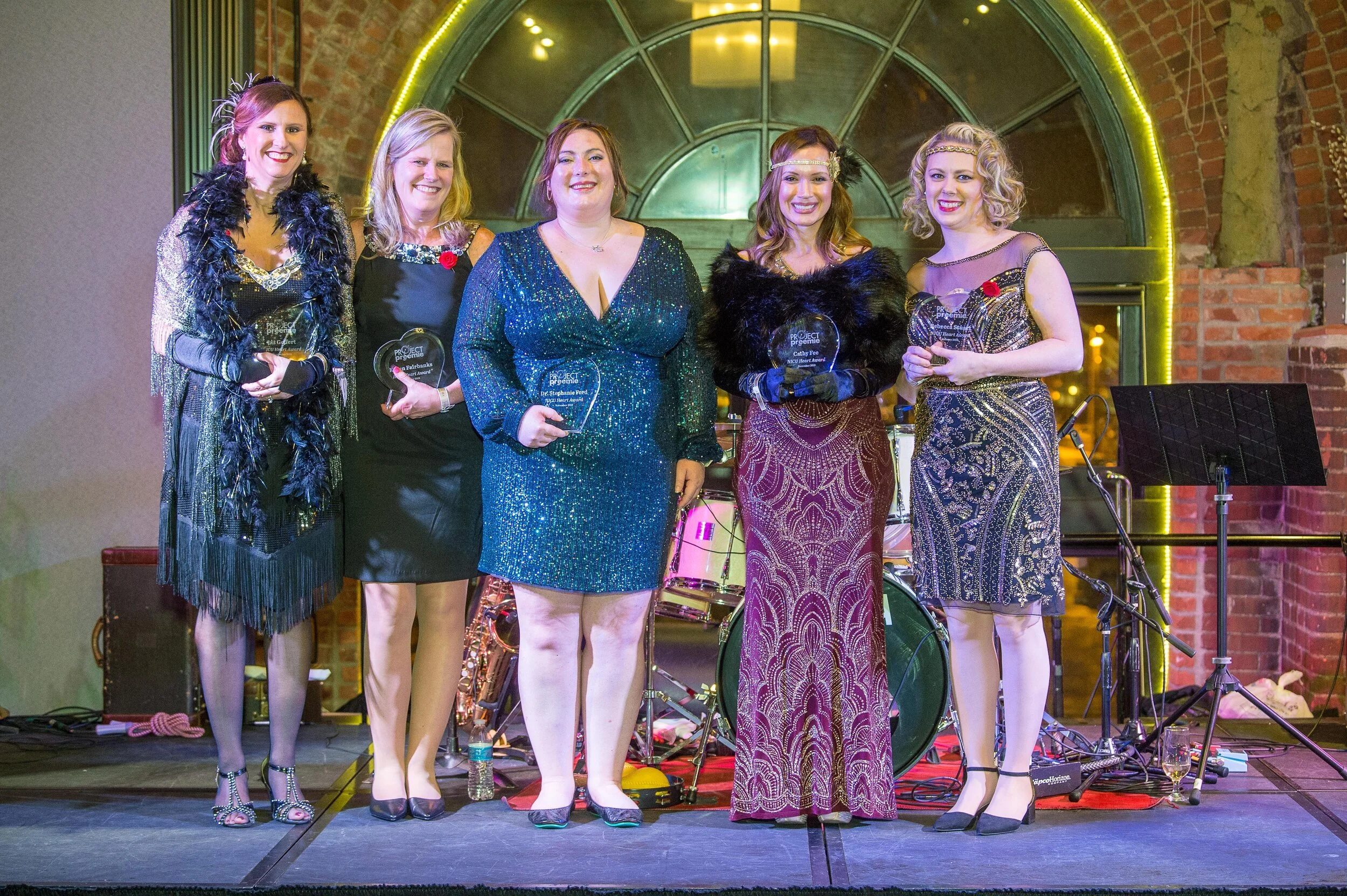 Happy child wearing glasses and a gray sweater with arms raised.