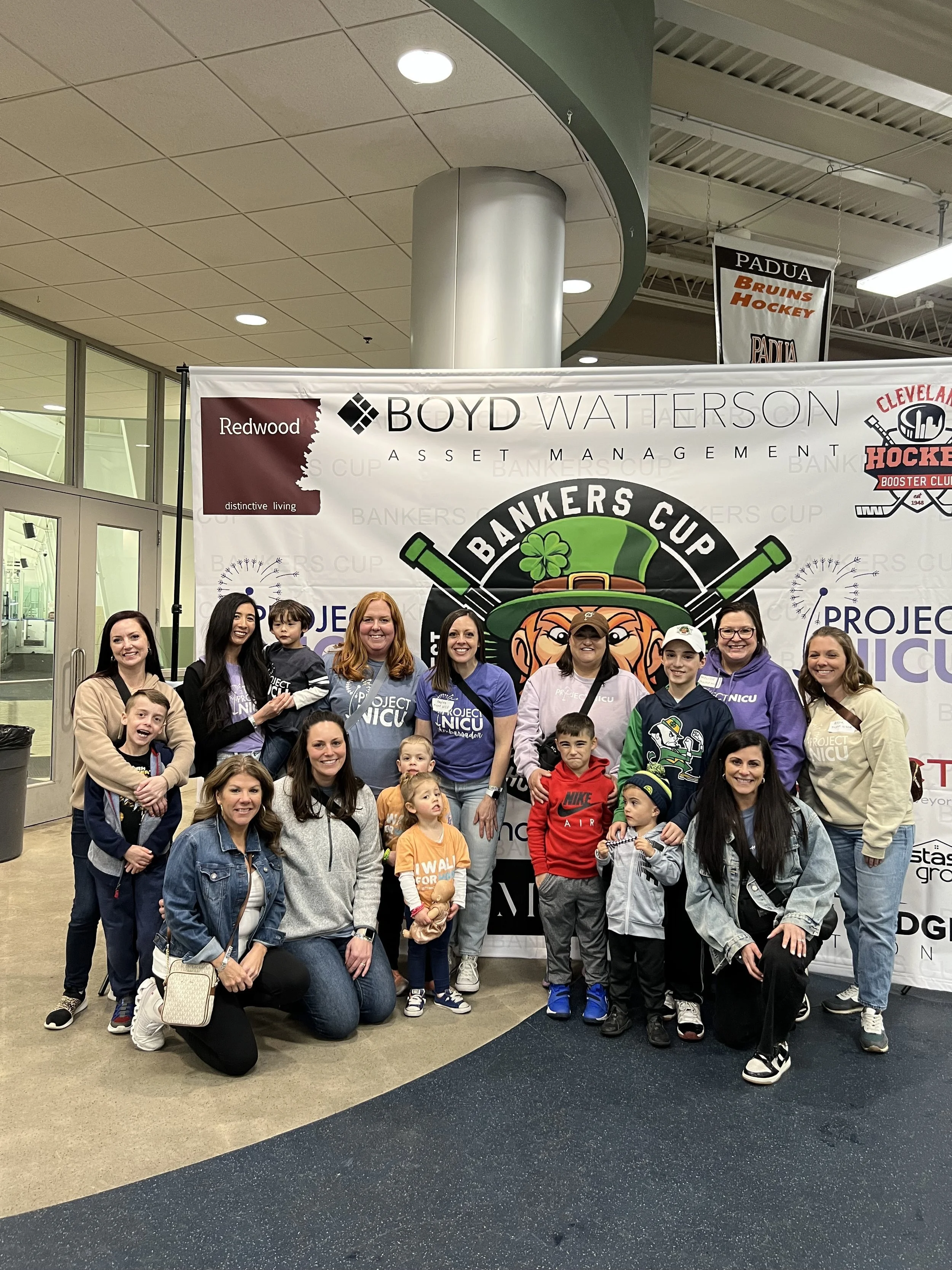 Happy child wearing glasses and a gray sweater with arms raised.