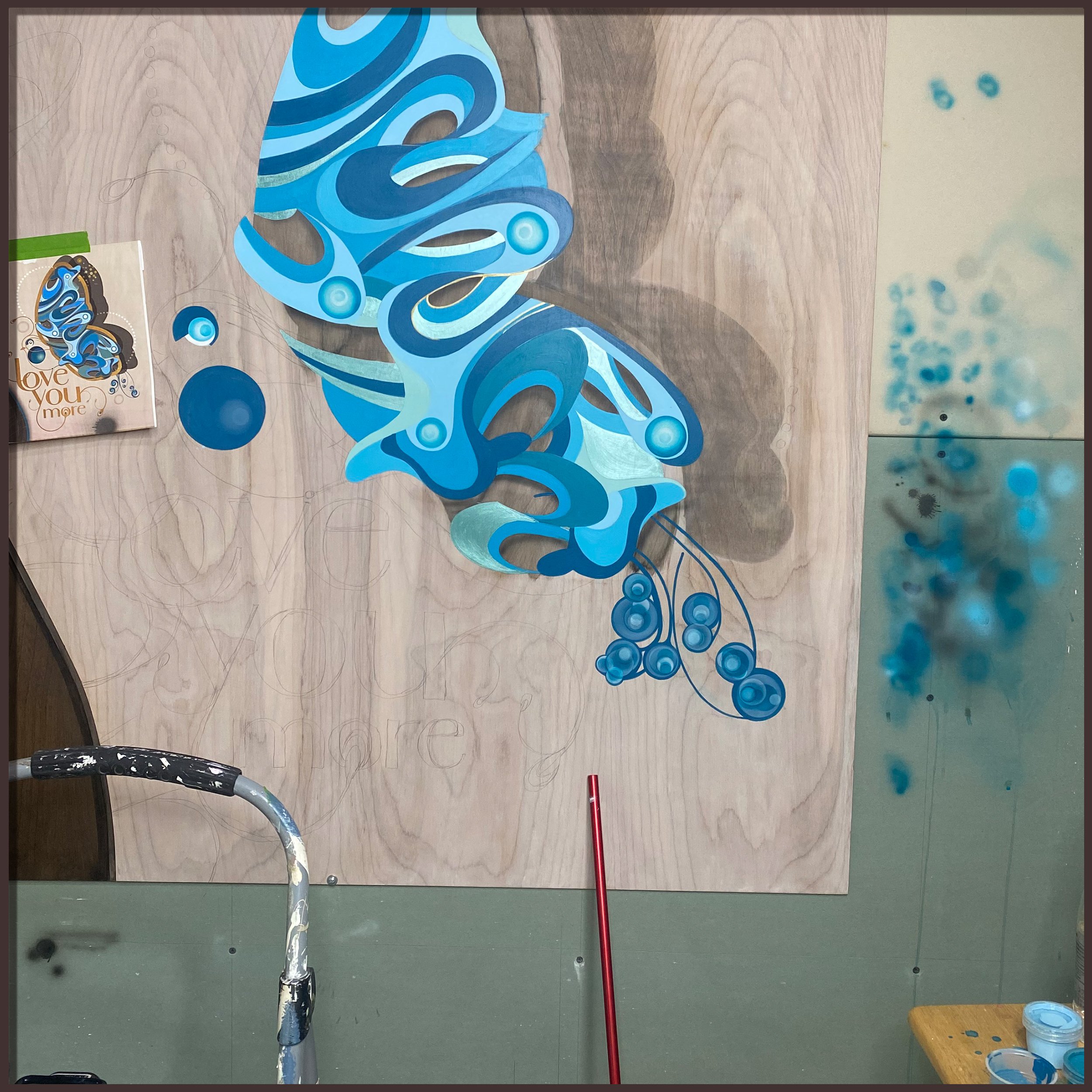 Hand-painting blue butterfly wing details on wood panel in studio
