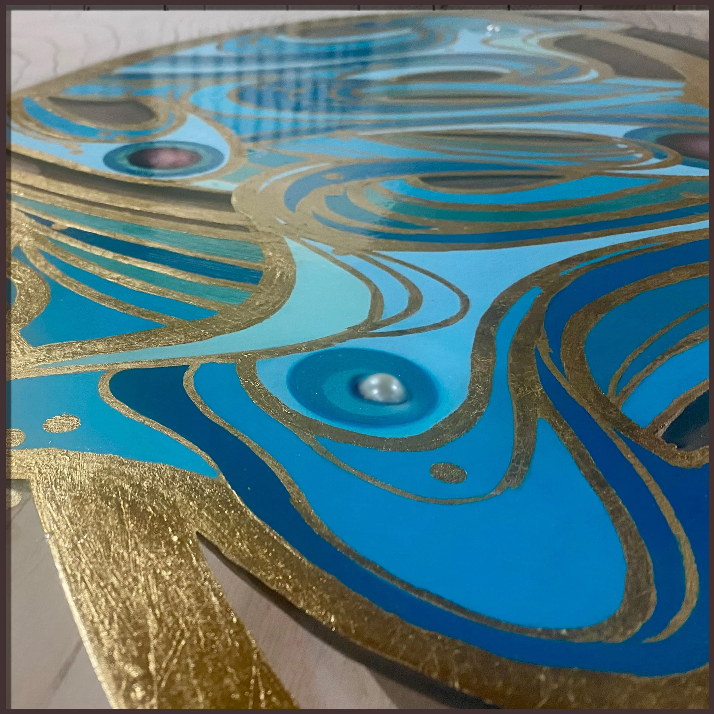 Close-up detail of blue and gold butterfly with 24k gold leaf on natural wood