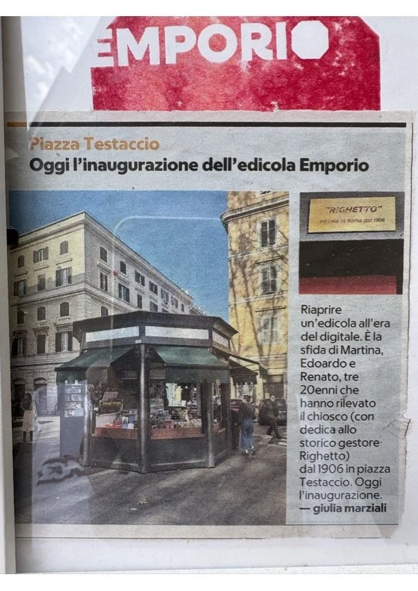 Un giornale che annuncia l'inaugurazione di una nuova edicola chiamata Emporio in Piazza Testaccio, con una foto dell'edicola e un breve testo descrittivo.