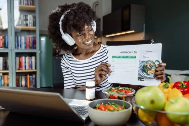 Woman with headphones smiling at a nutrition plan and healthy food on a table