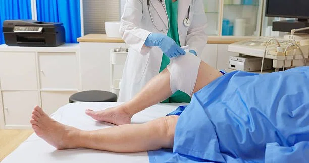 Doctor preparing to perform a medical procedure on a patient's leg in a clinical setting.