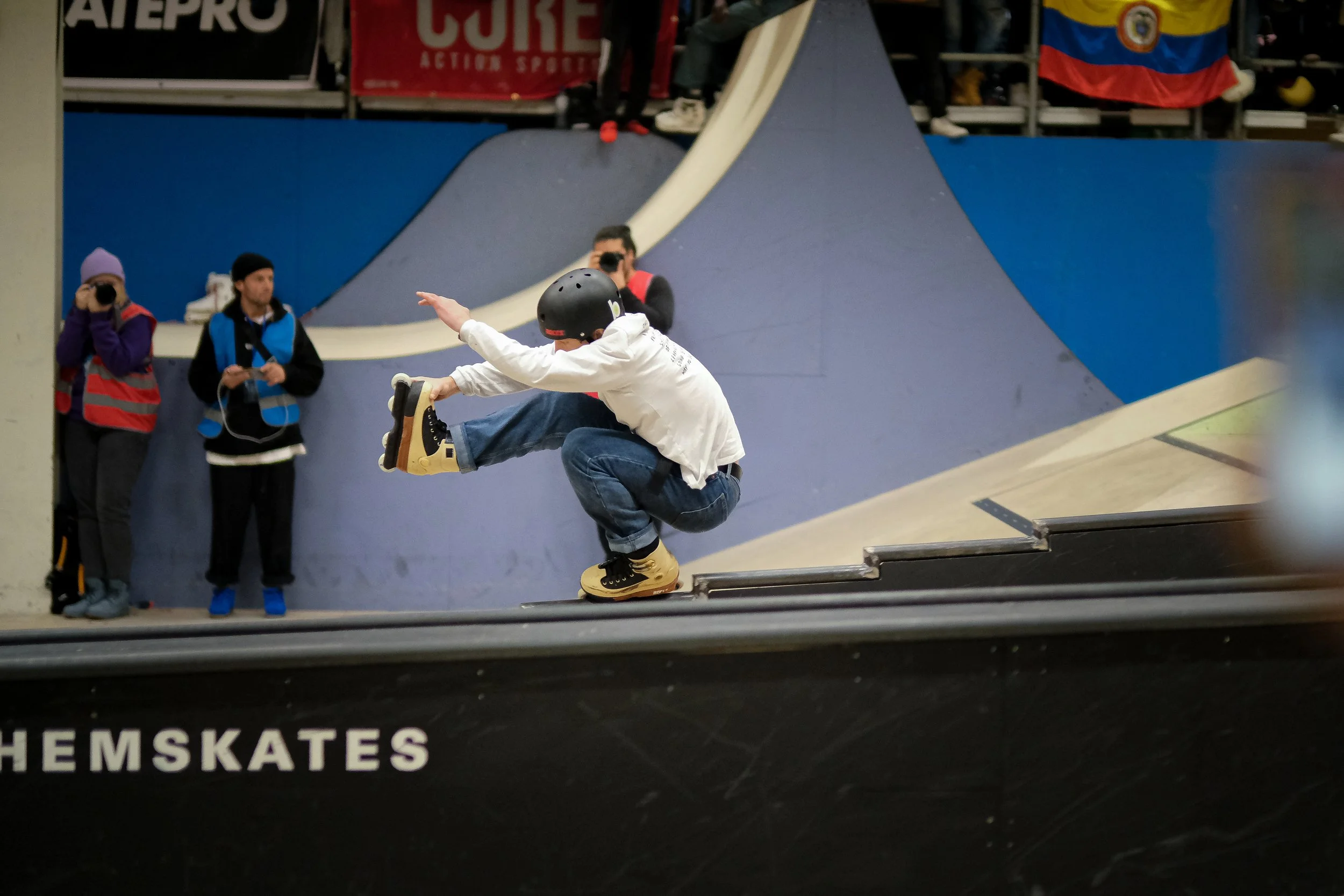 Een man met een helm dat op inlineskates springt op een skatebaan. soulgrind