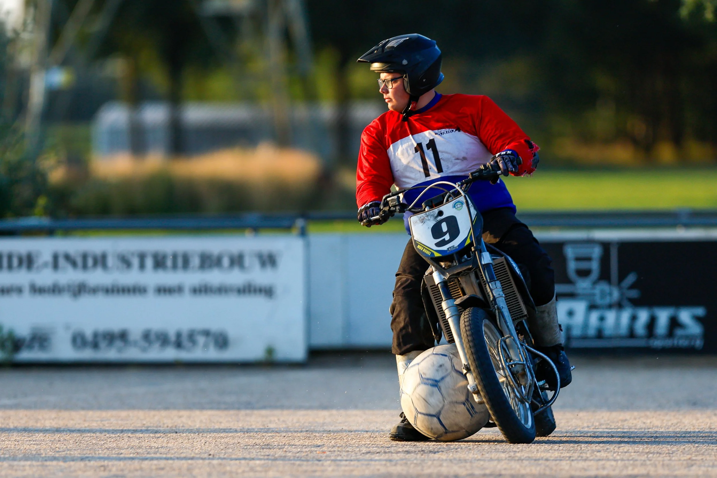 Een motorcoureur in een rood-wit-blauw trui met het nummer 11 op zijn borst, speelt motoball. gefotografeerd door Niels van Tongerloo van VTV portraits