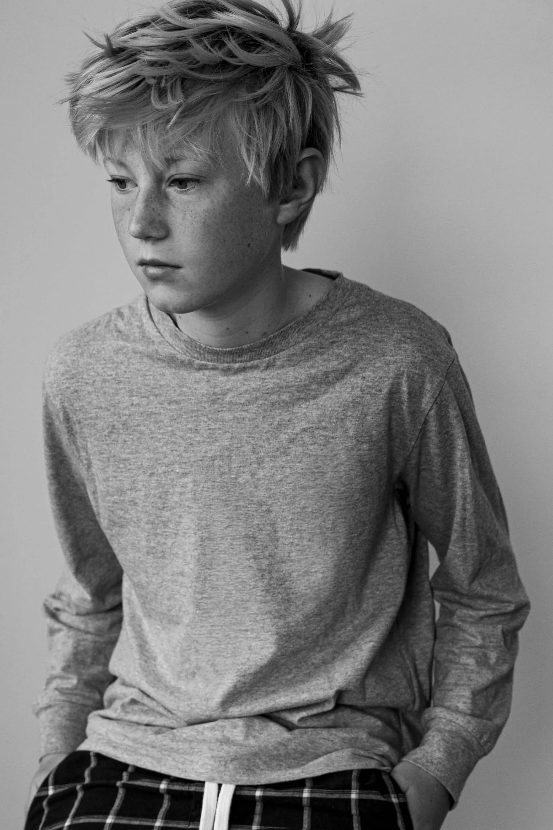 Black and white portrait of a young person with short hair and freckles, photographed by Studio Trois Pommes