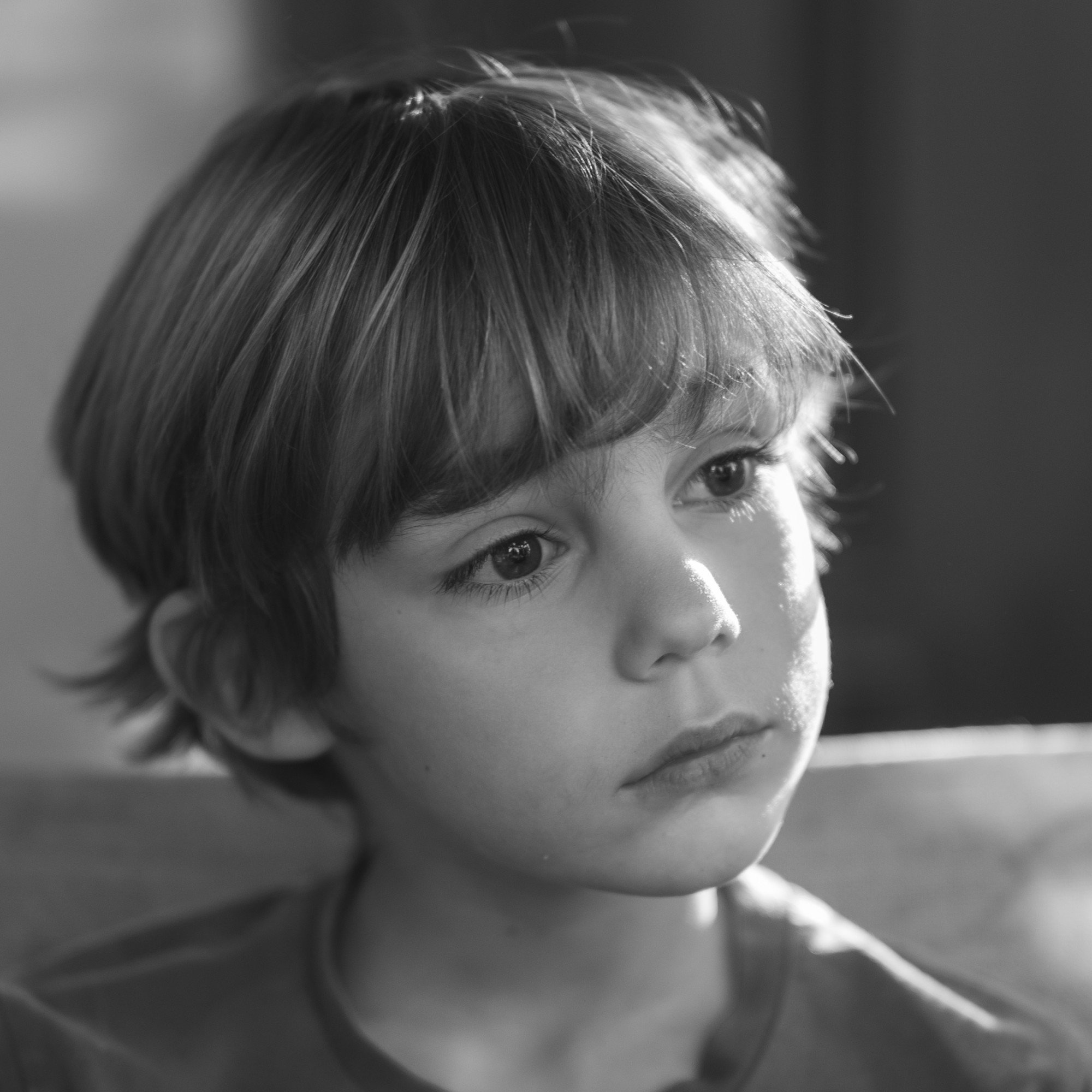 Black and white portrait of a child in soft backlight with a dreamy expression, by Studio Trois Pommes