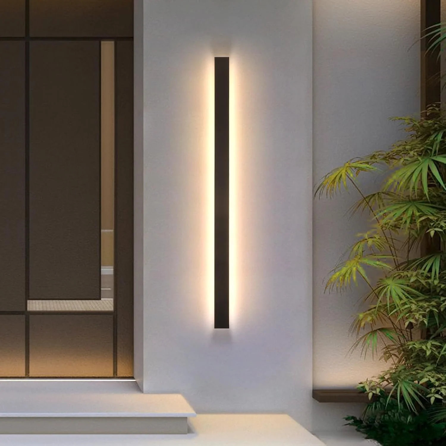 Modern wall light fixture with horizontal orientation on a white wall, with a small plant on the right side.