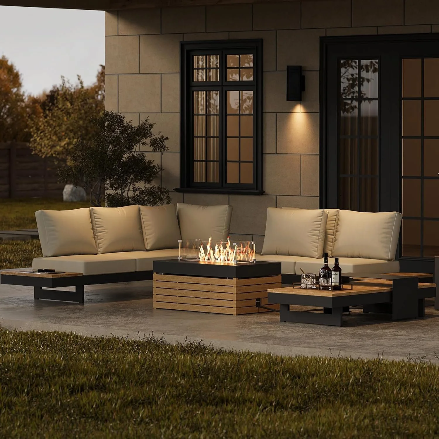 Outdoor patio with beige sectional sofa, fire pit, and side table with bottles of alcohol at dusk.
