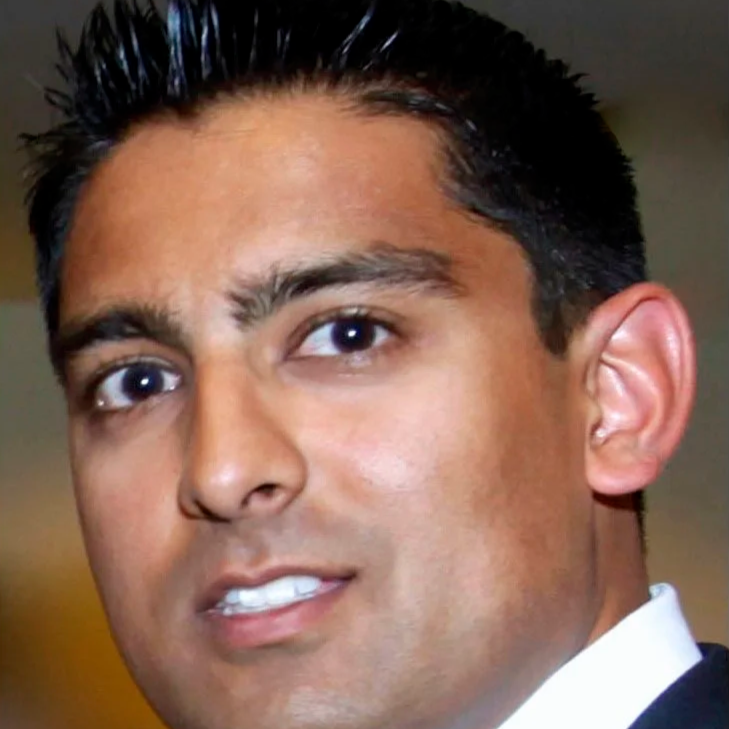 Mr Atwal. Close-up of a man with short dark hair, tan skin, and wearing a suit and tie.