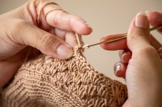 Person crocheting with beige yarn and knitting needles in Atanquez, Colombia.