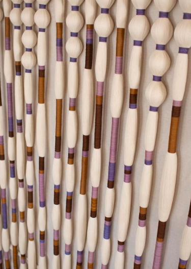 Close-up of thread installation with purple, brown, and pink painted accents arranged vertically.