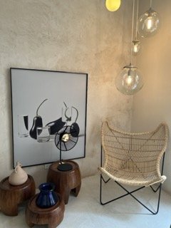 Decorative interior corner with modern art, glass pendant lights, and a woven chair. Bogota.