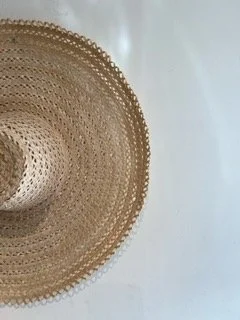 Close-up of a woven straw or wicker hat with a wide brim against a plain white background.
