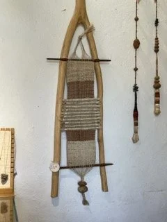 Backstrap loom made of wooden sled with woven seat.