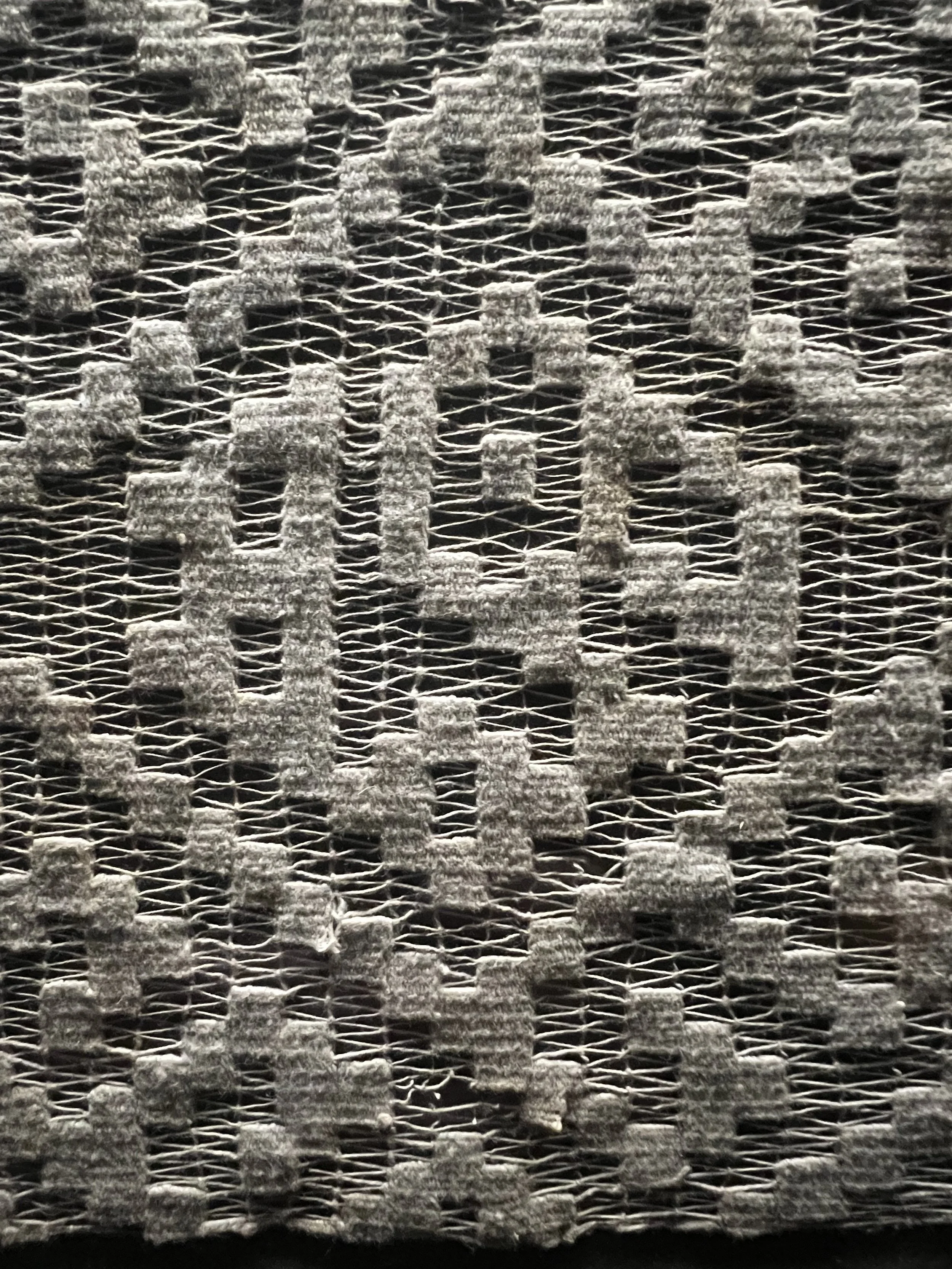Close-up of a woven Peruvian fabric with a geometric pattern in natural tone.
