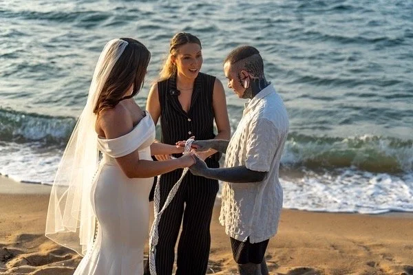 Destination wedding officiant overseeing a vow exchange between a diverse couple on a white sand beach in Puerto Rico.