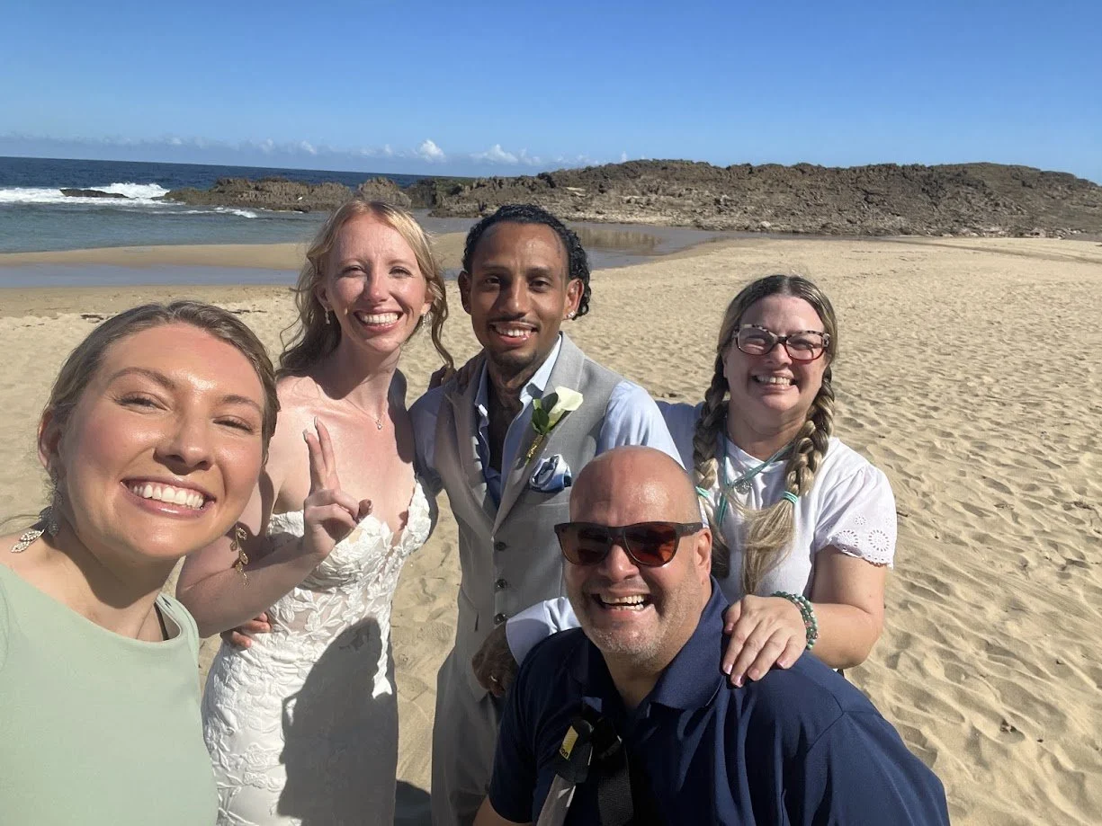 Paradise Vows PR founder Kendra smiling on the beach with a destination wedding clients and members of the wedding party. 