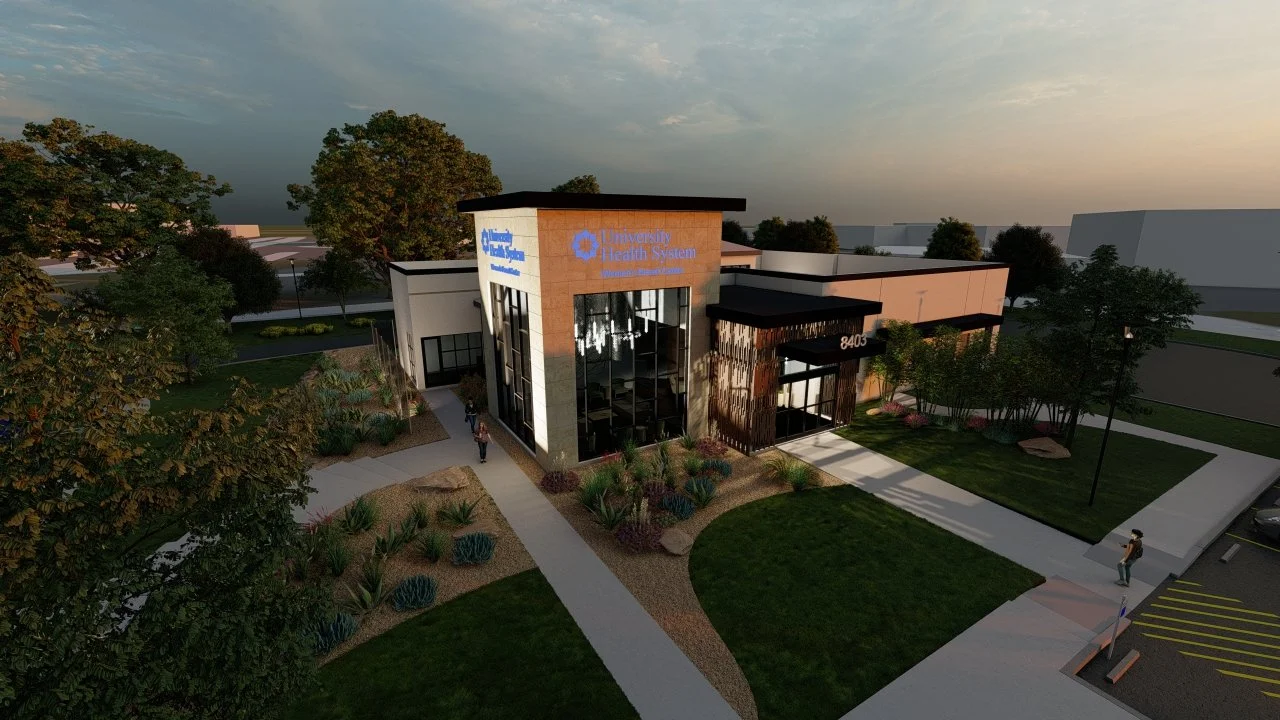 A modern building with signs for University Health System, surrounded by landscaped greenery, trees, and a parking lot, during dusk.