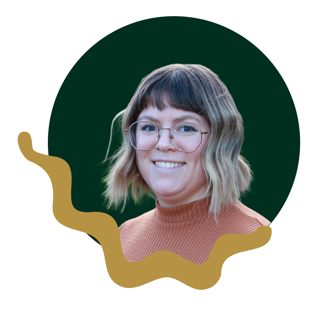 A woman with shoulder-length wavy blonde hair, wearing large round glasses and a burnt orange turtleneck sweater, smiling at the camera.