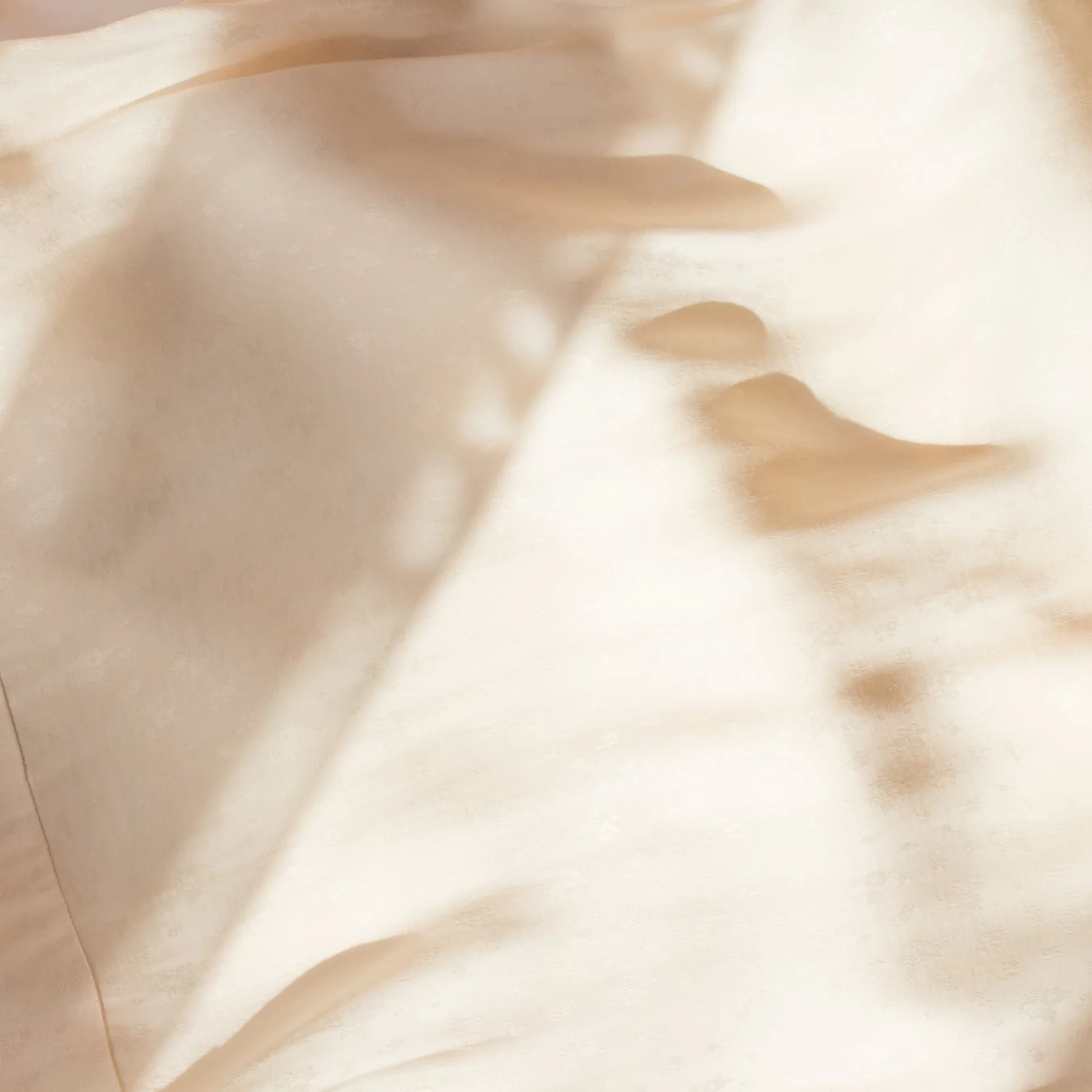Close-up of a light-colored fabric with gentle folds and shadows.