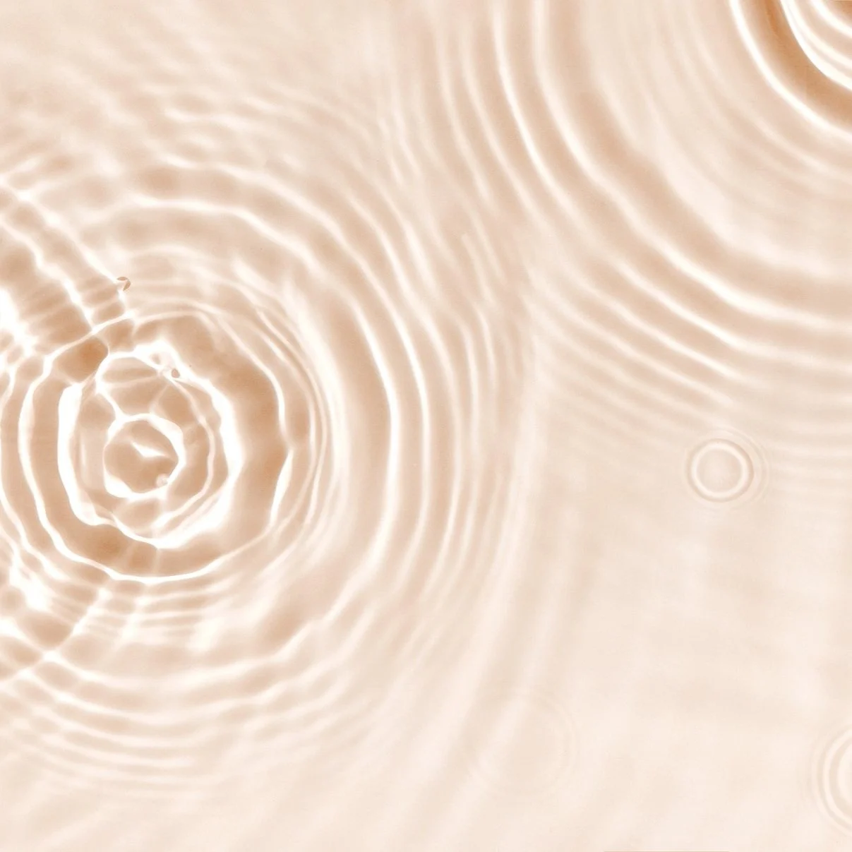 Close-up of water with ripples and concentric circles caused by raindrops or objects falling into it, creating a reflective surface.