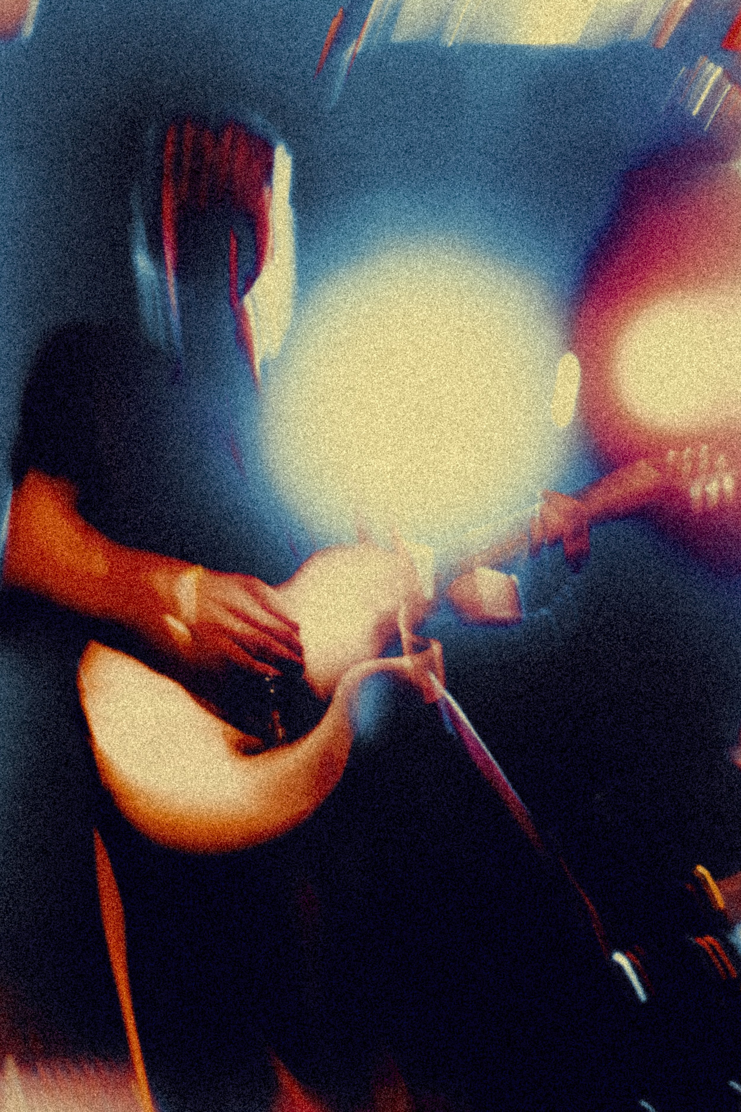 A psychedelic photo of a musician with long hair, wearing headphones, holding a microphone, with a bright light source behind him in a dark setting