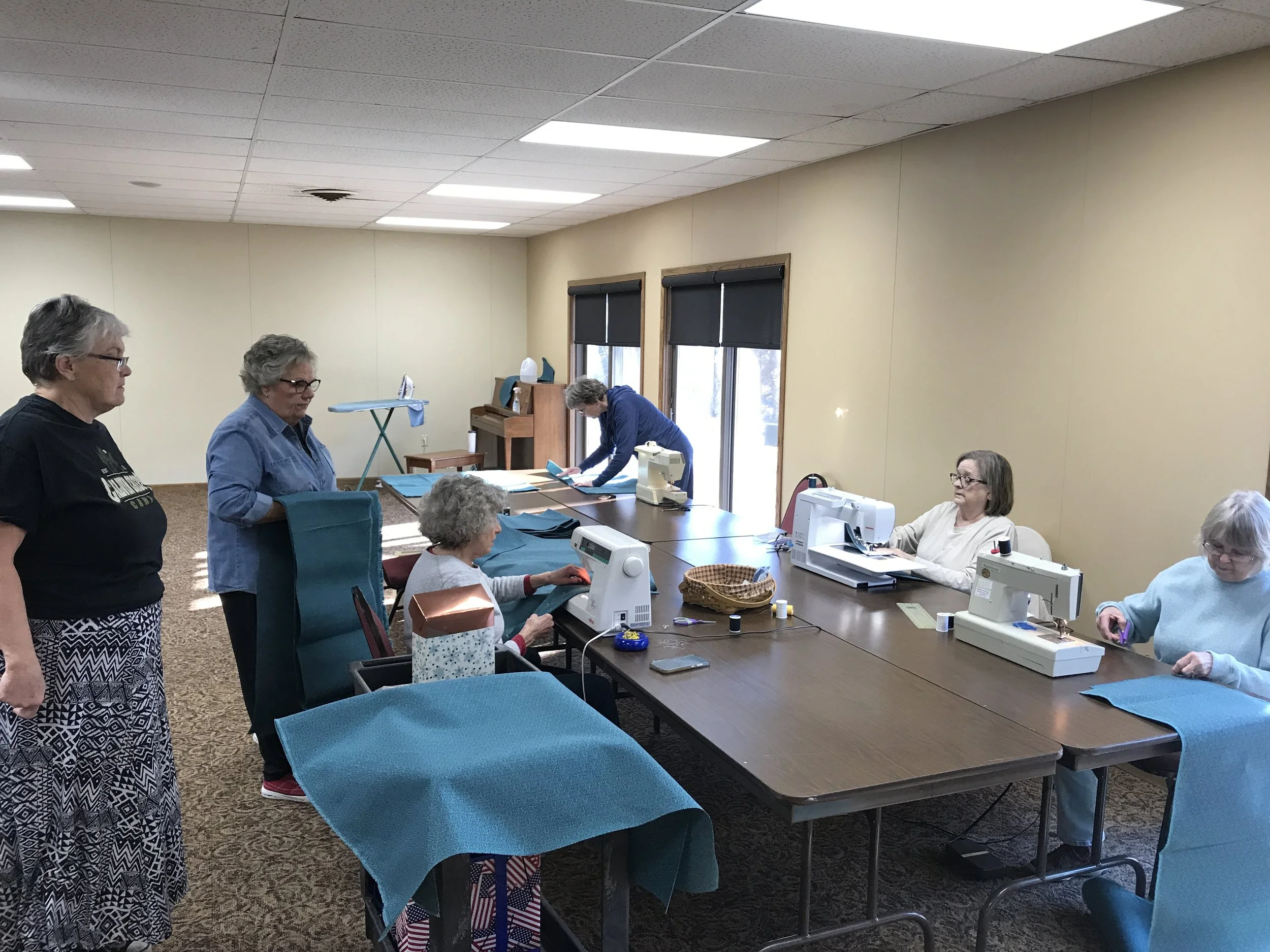 Women working on sewing machines in a classroom with two women watching.