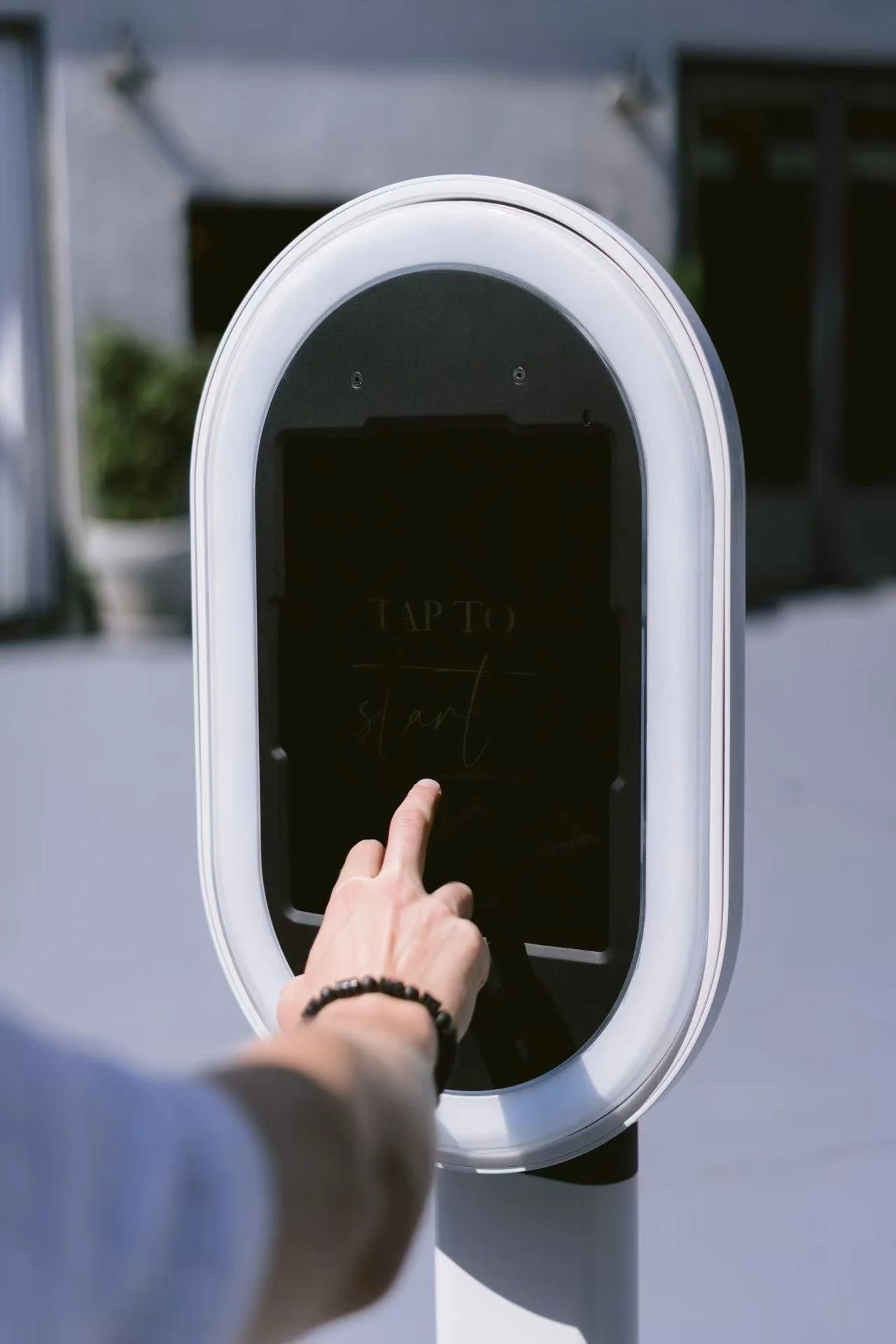 Person touching a digital screen at a modern outdoor self-service kiosk
