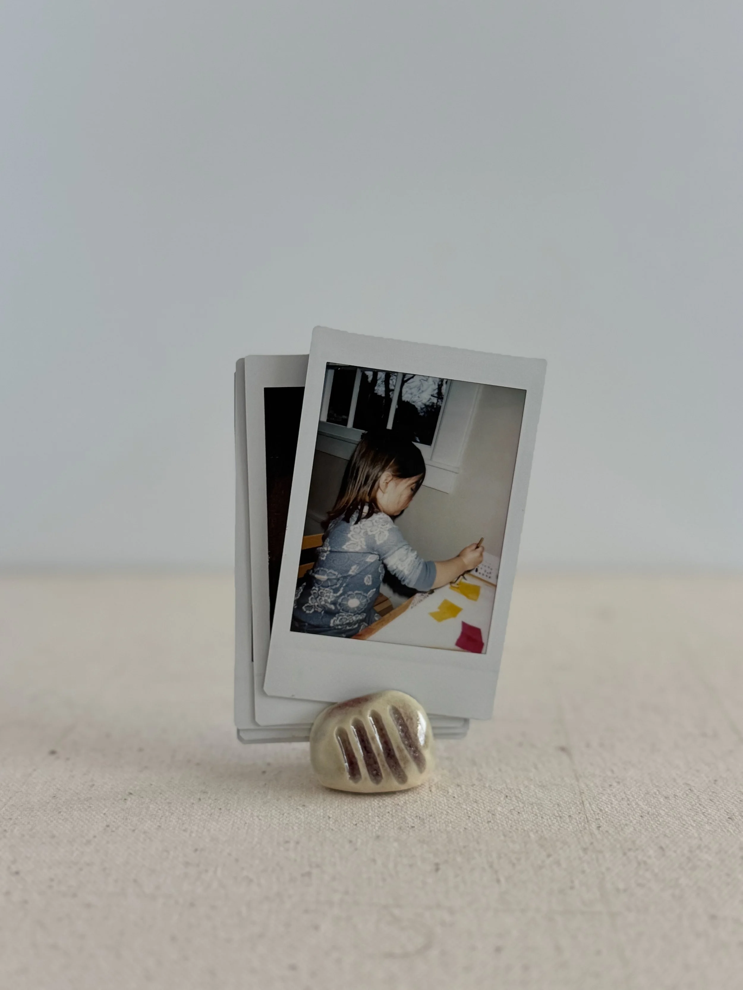 A set of two install photos in a handmade ceramic photo or card holder.