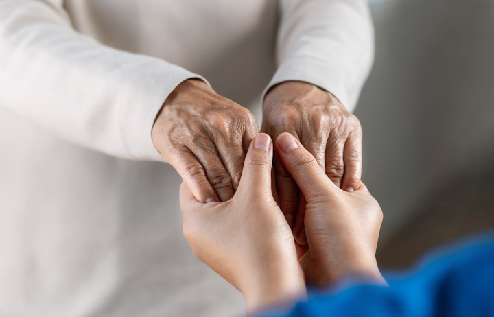 Two hands holding each other, one appearing older and the other younger, in a gesture of comfort or support.