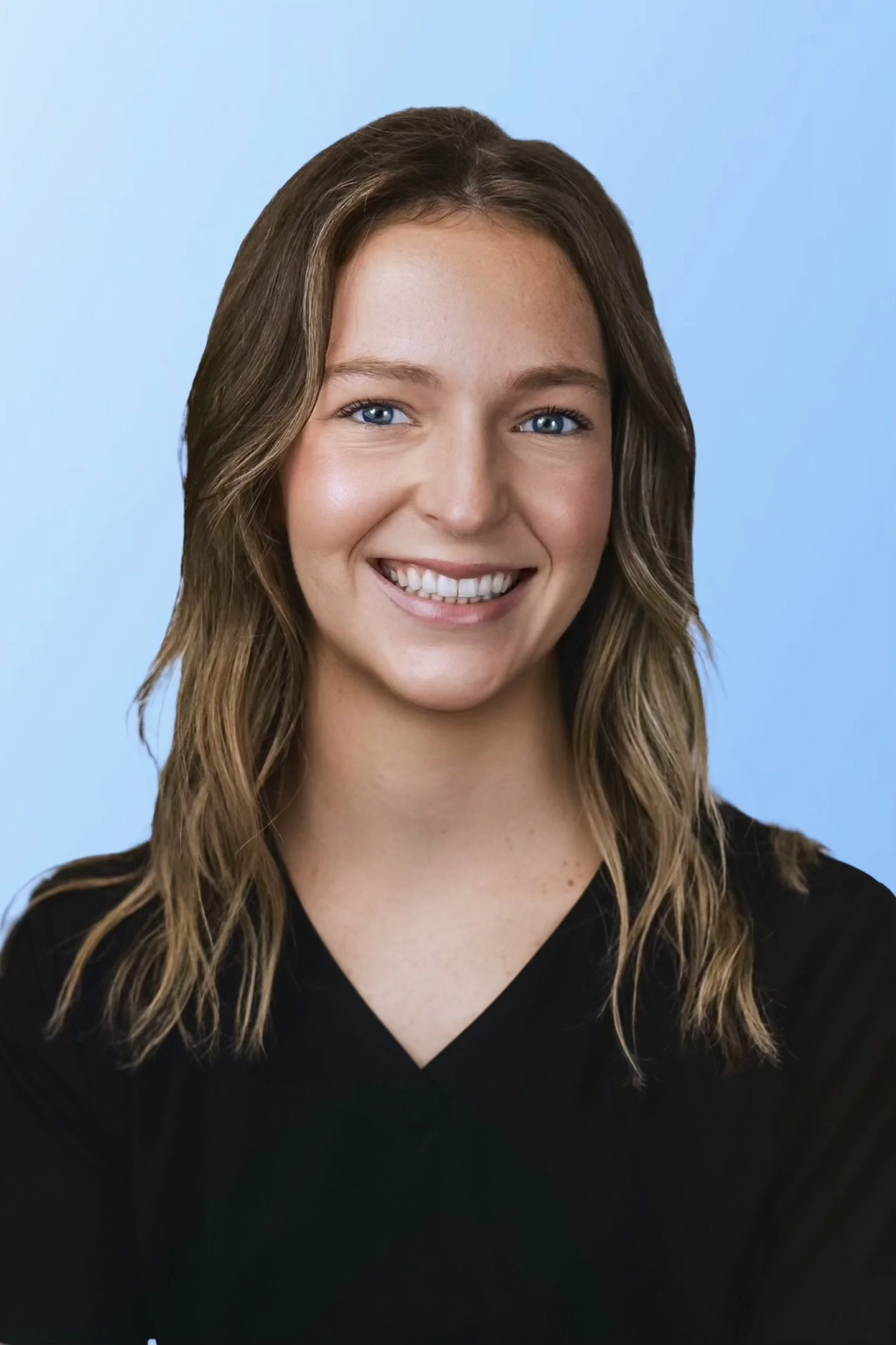 Jeune femme avec des cheveux bruns ondulés, souriante, portant un haut noir, contre un fond bleu clair.