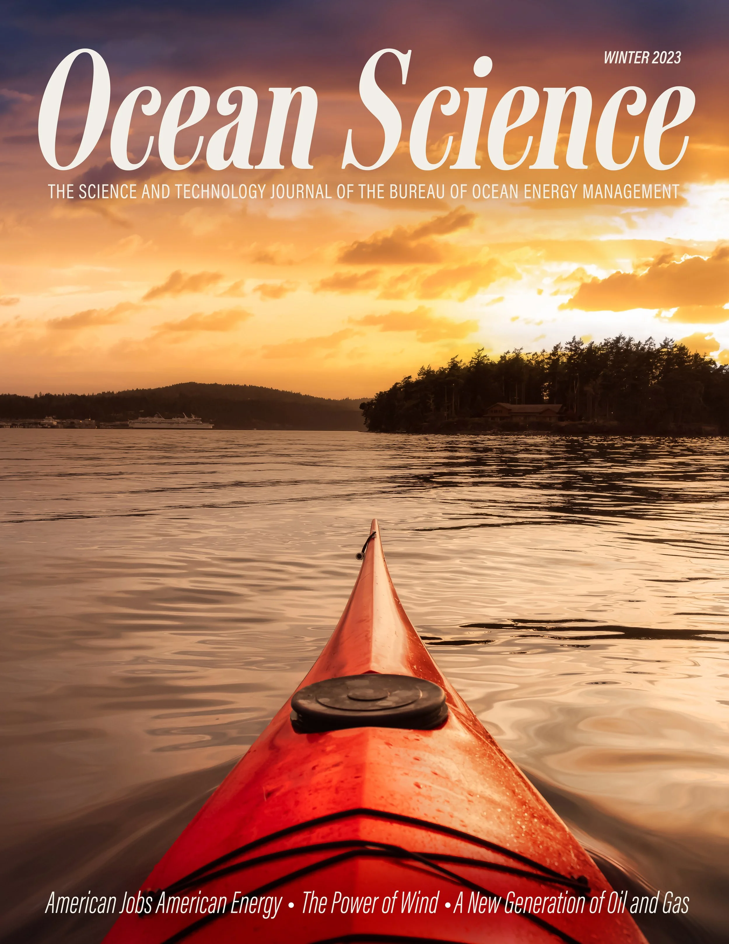 Cover of Ocean Science magazine, Winter 2023 issue, showing a view from a kayak on a calm body of water at sunset with trees and hills in the background.