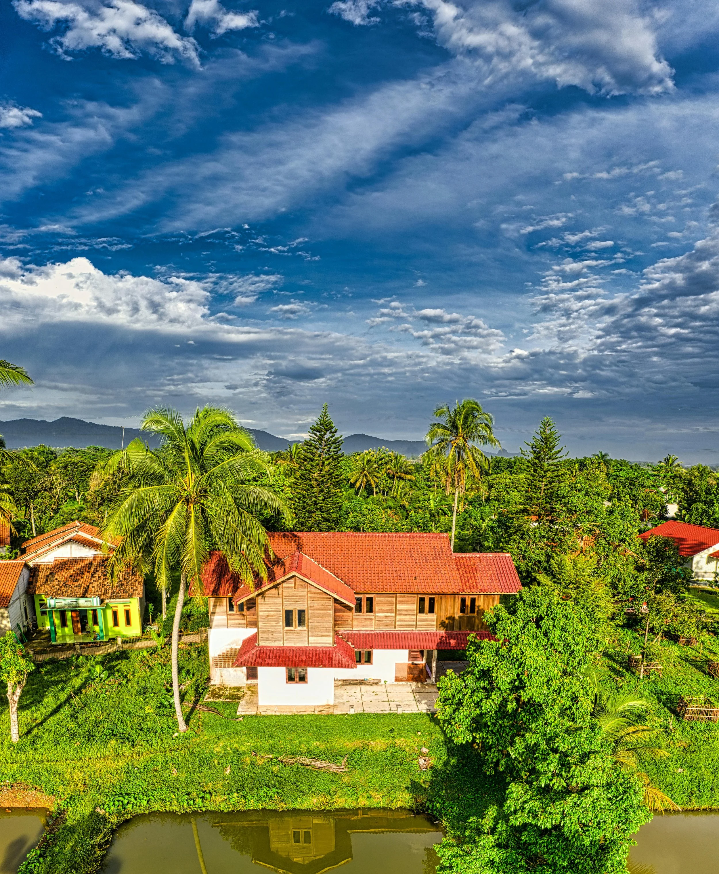Photo of a South Florida home with a red roof surrounded by palm trees - example of residential aerial photography.