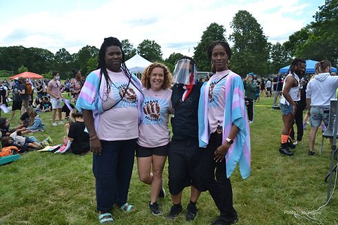 Group of people at an event. Three people are wearing Trans Resistance t-shirts. one person is wearing black and a face shield.