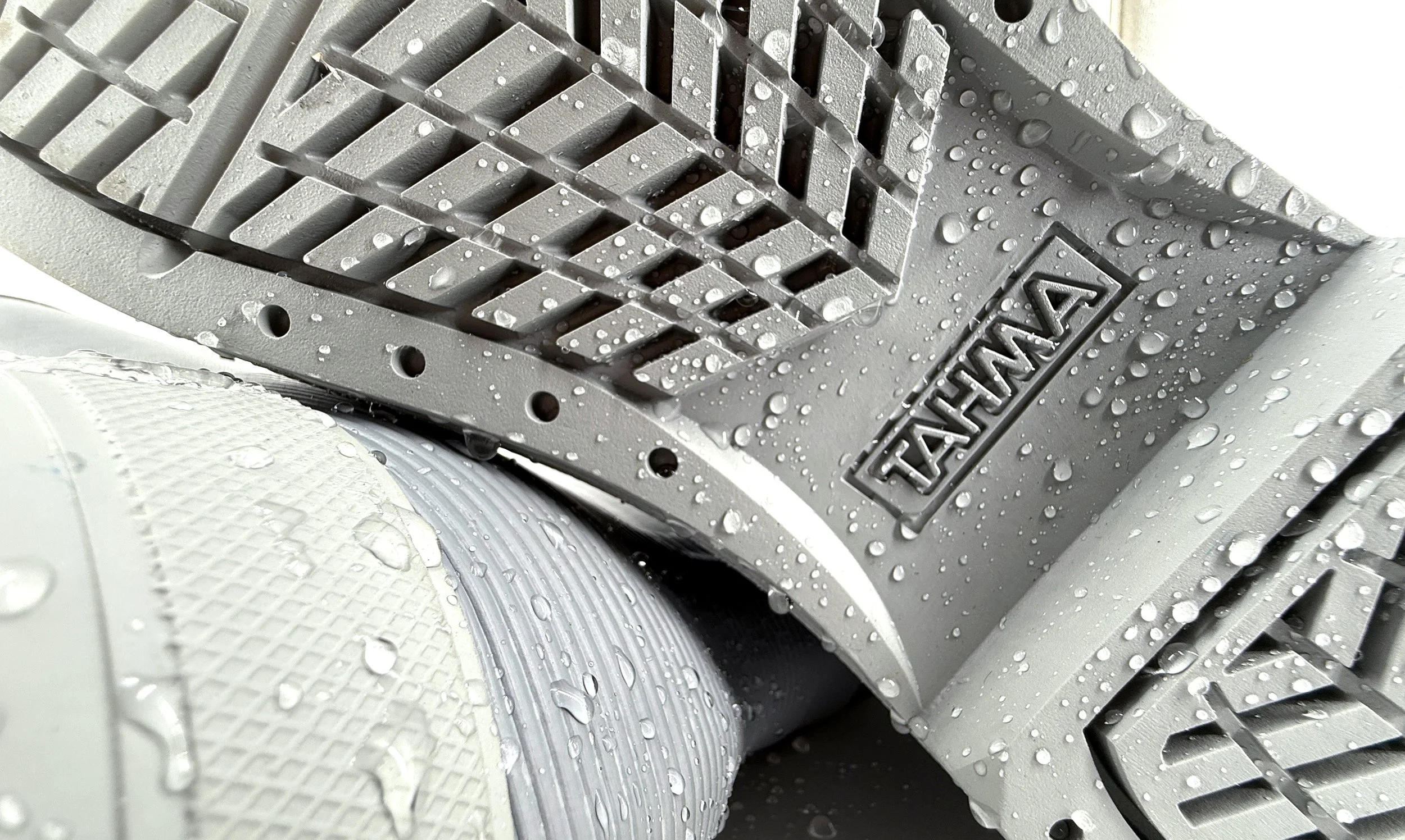 Close-up of wet Tahma work boot outsoles covered in water droplets, showing the slip-resistant tread pattern.