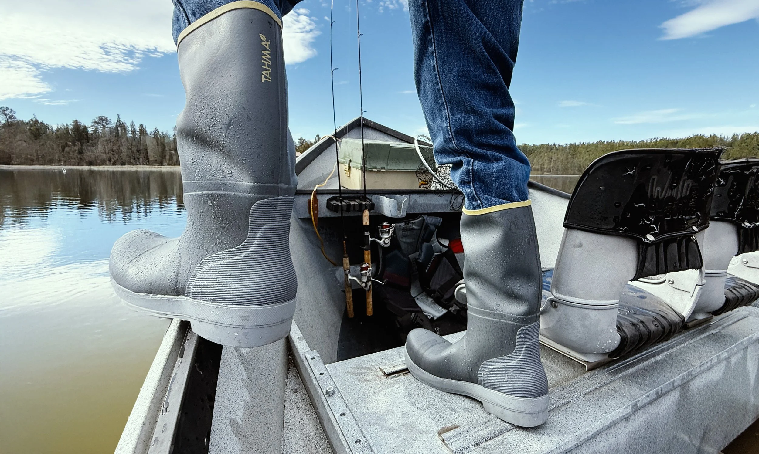Tahma 15 inch boots standing on the edge of a small fishing row boat on a lake