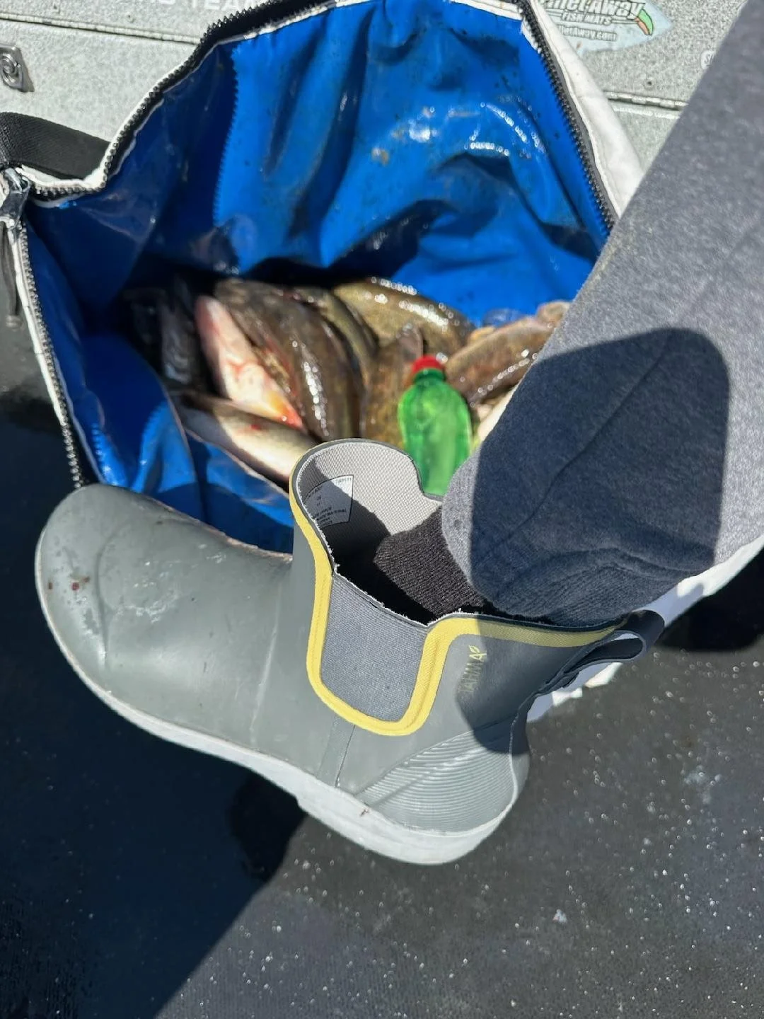 Customer wearing low-cut Tahma boot standing next to a bag of fish caught that day