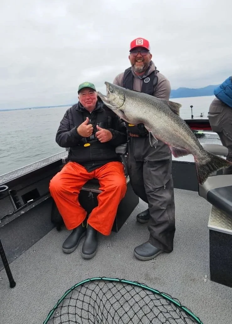 2 customers wearing Tahma boots on a fishing boat showing off a huge fish just caught on a small fishing vessel
