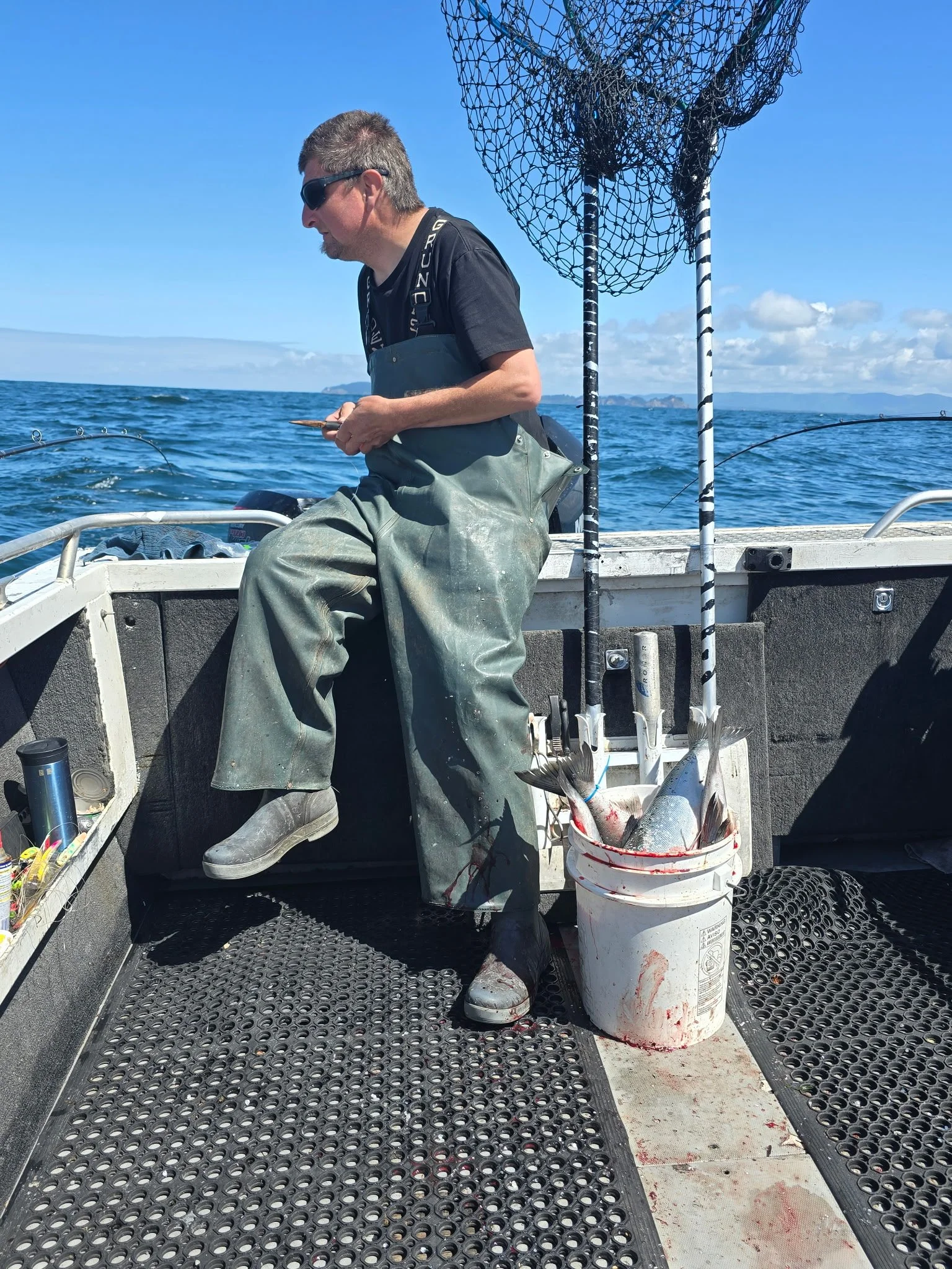 Customer wearing tahma boots on the back of a commercial fishing vessel on a sunny day