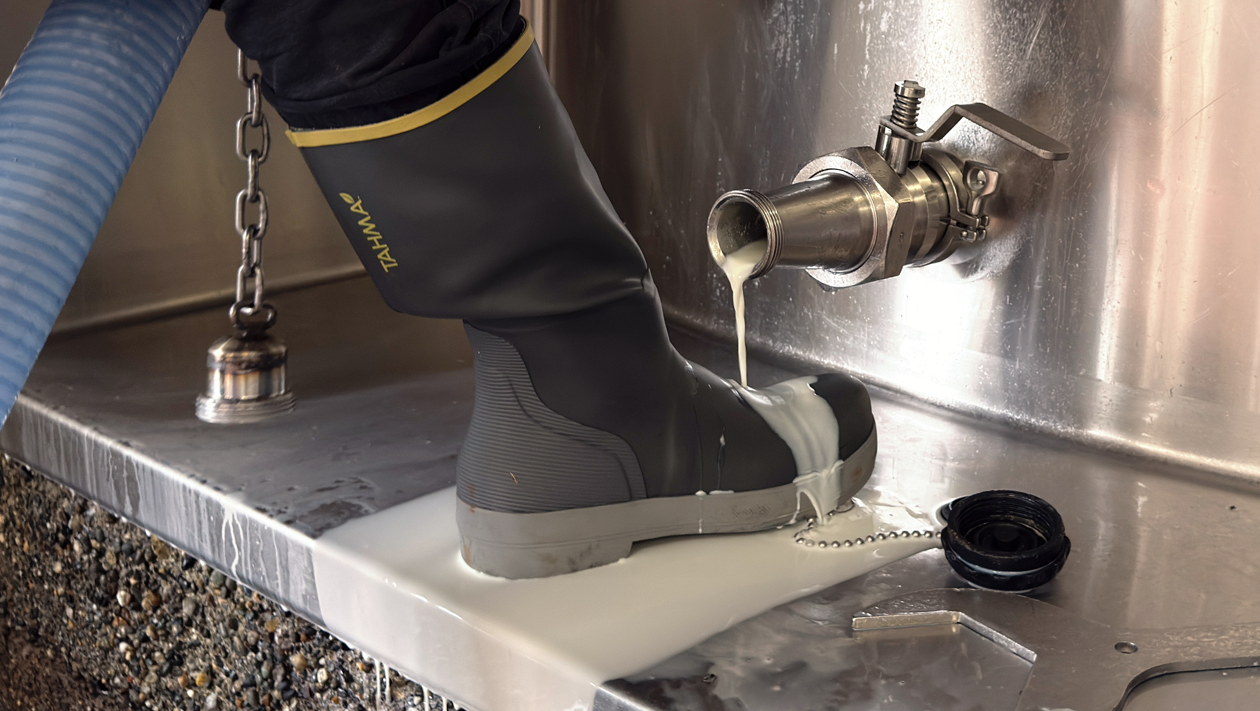 Tahma boots with milk being spilled on them from at a dairy processing center