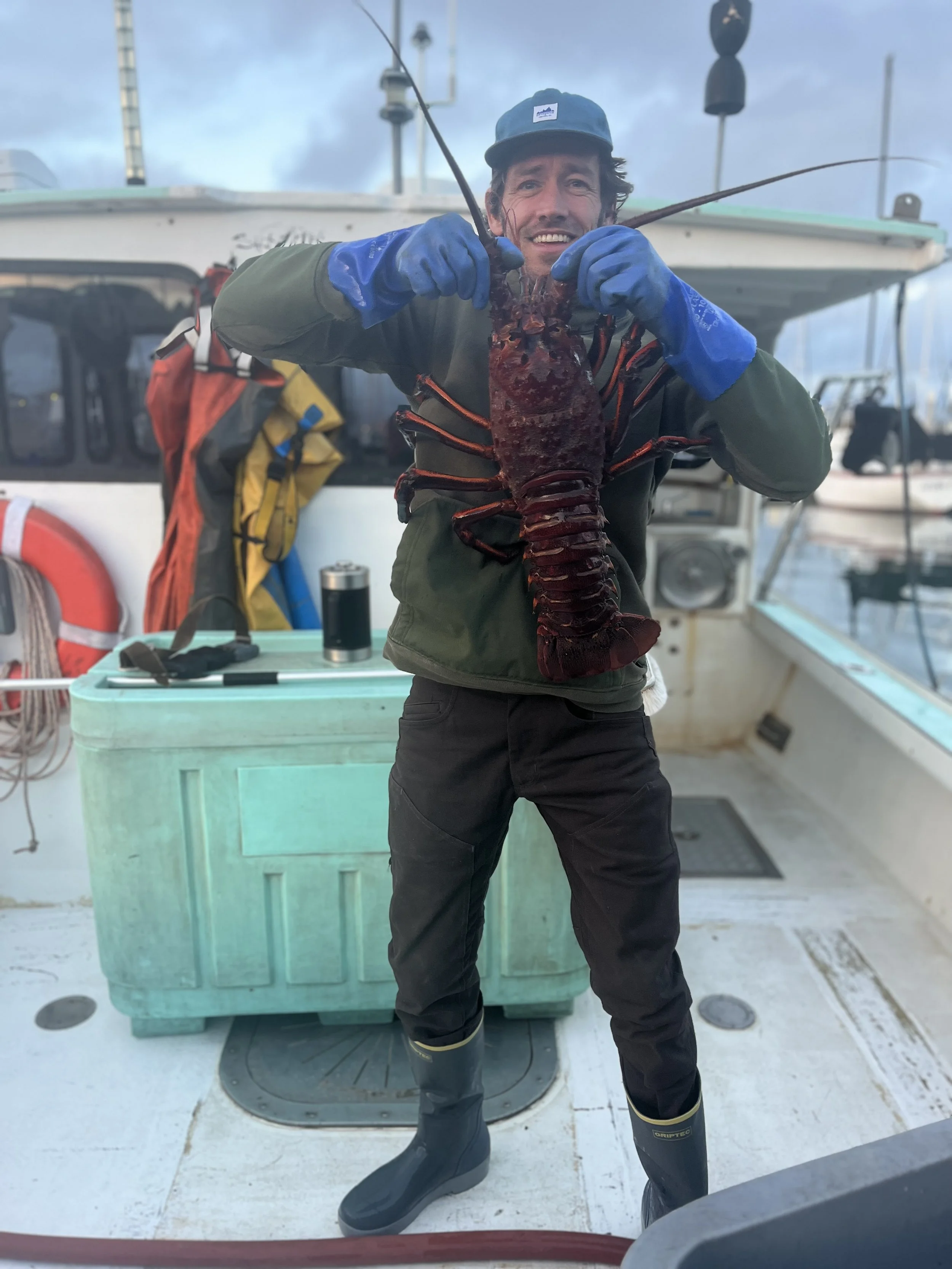 Tahma boots worn by a commercial lobster fisherman holding a lobster on a boat at sea