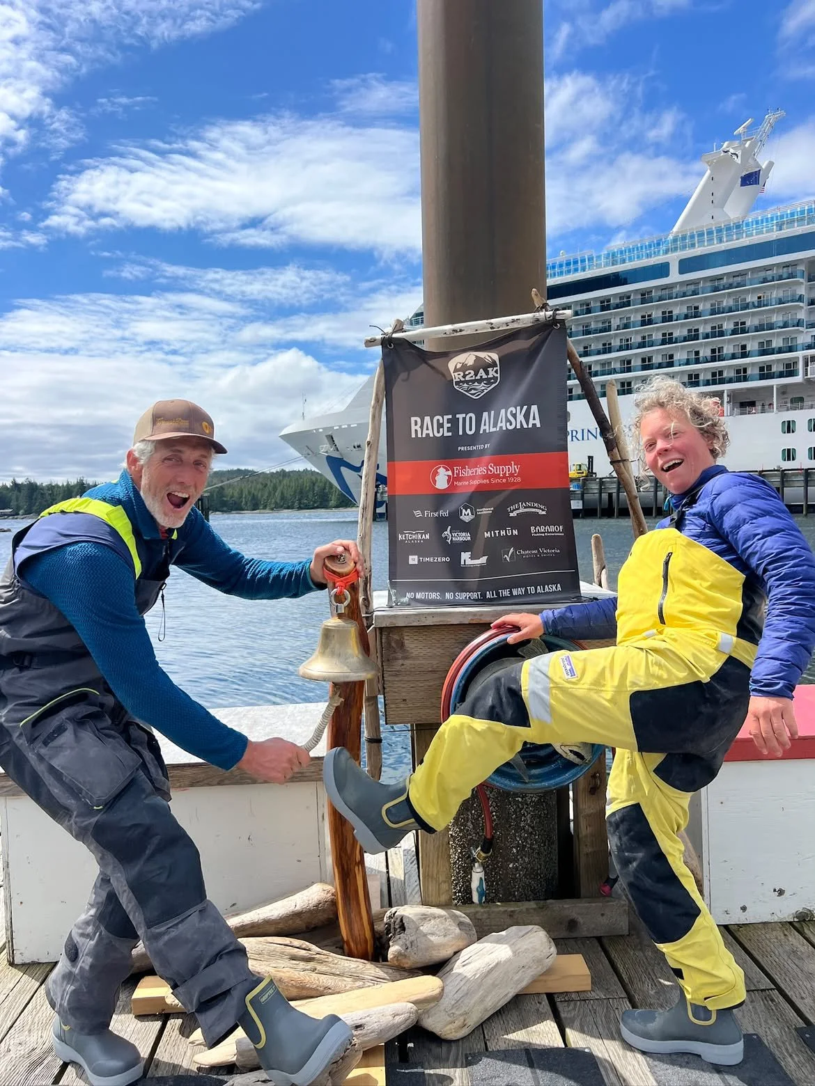 Customers wearing Tahma boots standing in front of a sign Race to Alaska before sending off