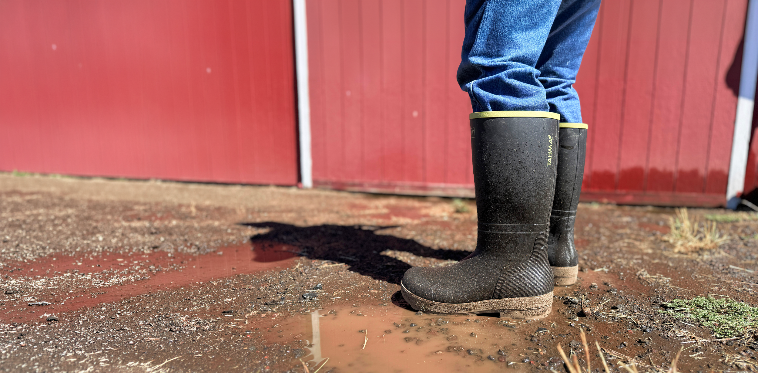 Tahma All Terrain boots worn by farmer standing in front of a red barn