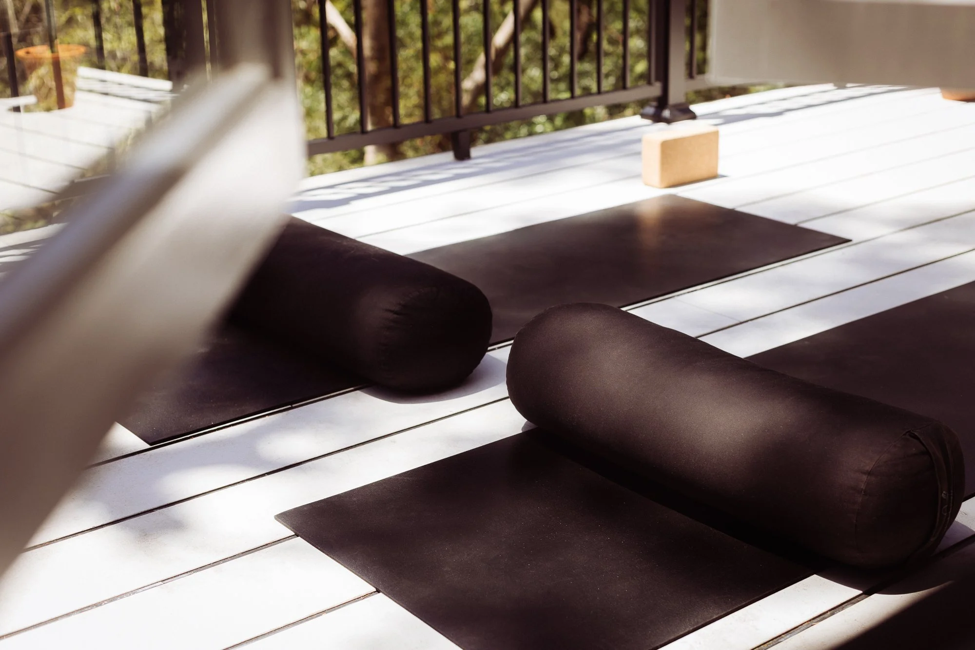 Yoga mats with bolsters on a wooden deck outside