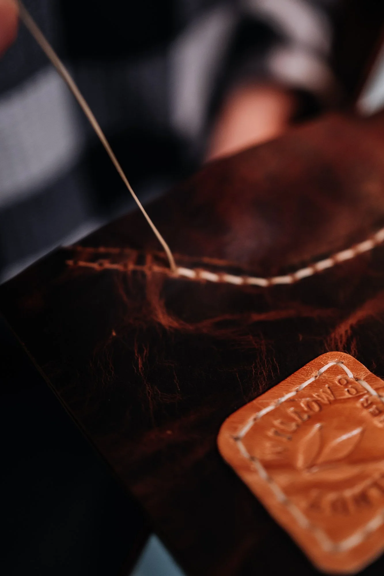 Close-up of a leather shoe, showing a textured surface and a leather tag embossed with the brand name 'Red Wing.'