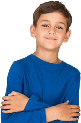 A young boy with brown hair and blue eyes wearing a blue long-sleeve shirt, smiling slightly with arms crossed.