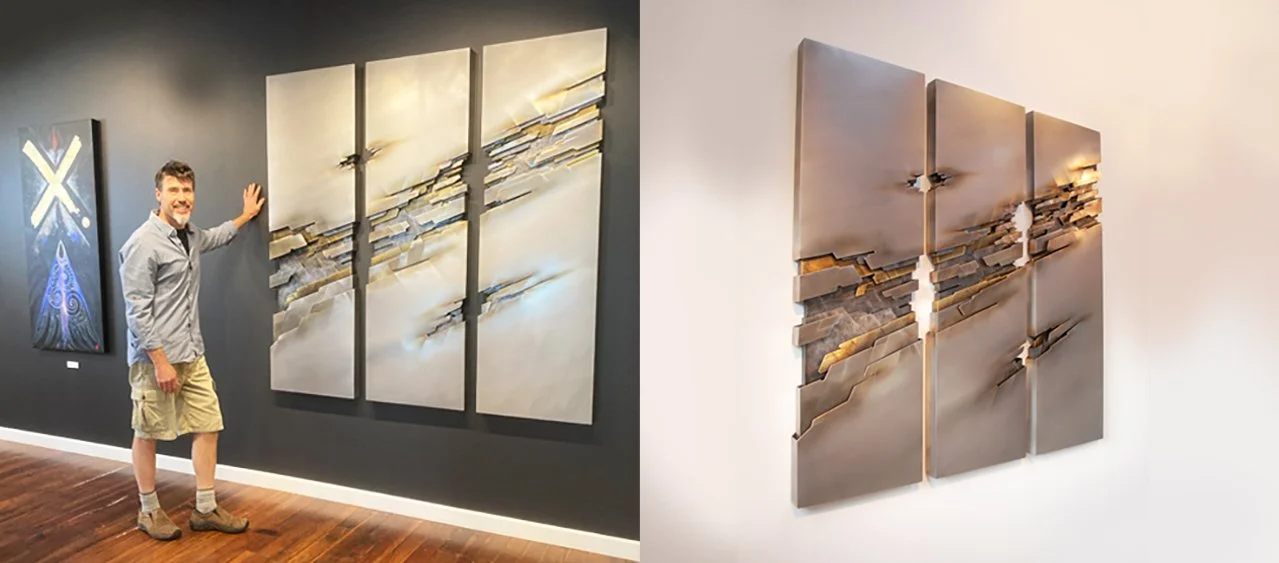 Two panoramic metal abstract artworks with layered textured sections, displayed on contrasting dark and light walls in an art gallery, with a man inspecting the piece on the dark wall.