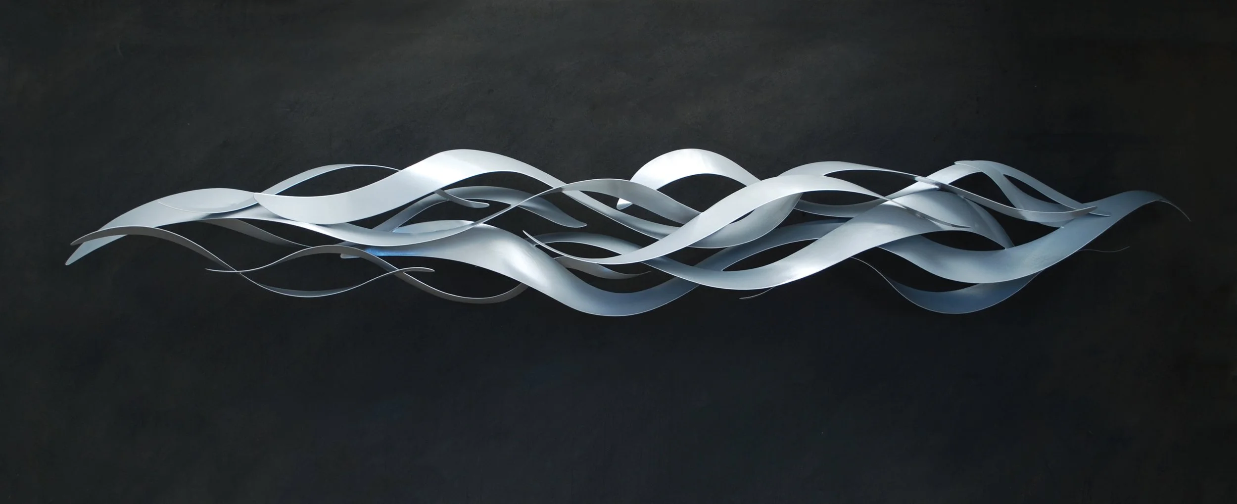 Modern metal wall art sculpture with intertwined, twisting silver strips against a dark background.