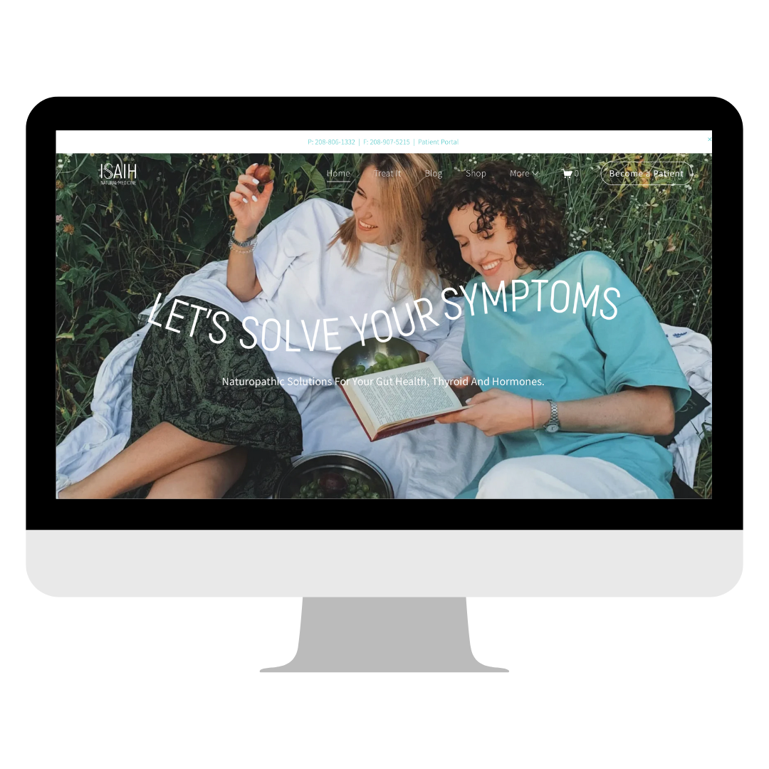 Two women lying outdoors, one wearing a white shirt and the other in teal, smiling and looking at a book, with greenery around them.